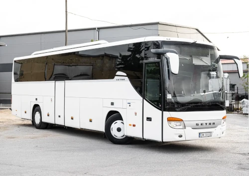 MAIN_MINI_bialy autokar turystyczny marki setra z przyciemnionymi szybami ustawiony pod katem z skreconymi kolami na industrialnym tle landscape